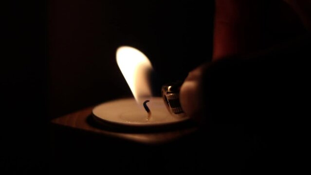 Close-up of flame burning on the candle isolated on a black background. Lighting wick with lighter