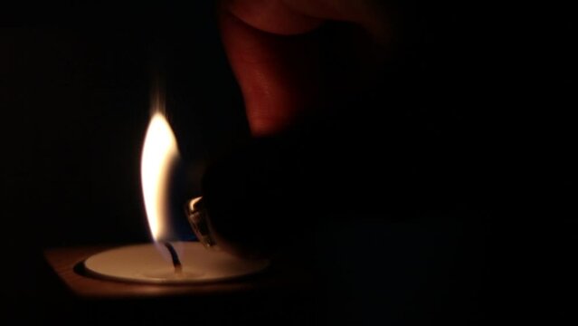 Close-up of flame burning on the candle isolated on a black background. Lighting wick with lighter