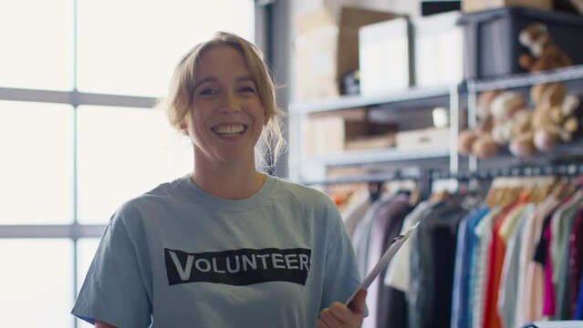 Portrait of female charity worker sorting through donations of clothing to thrift store - shot in slow motion