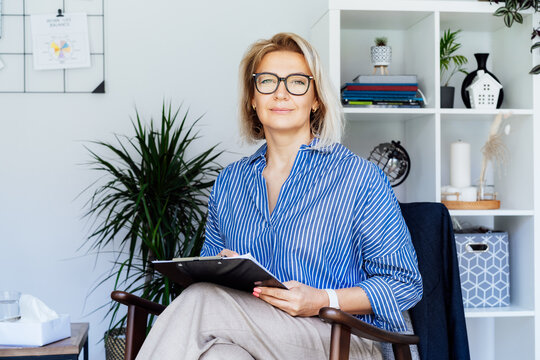 Professional Psychotherapy. Successful female Psychologist Smiling To Camera Sitting On armchair In Office. Mature 50s middle-age professional portrait of teacher, coach, mentor, therapist, counselor