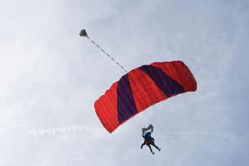 Deux personnes sautent en parachute avec une voile rouge dans le ciel