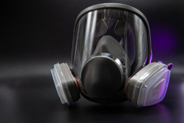 Full face gas mask respirator for personal protection of eyes and respiratory organs from harmful vapors, gases, radioactive dust. Black dark background. Selective focus. work equipment. medicine.