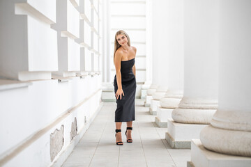 Obraz premium Portrait of a young beautiful blonde girl in a black dress
