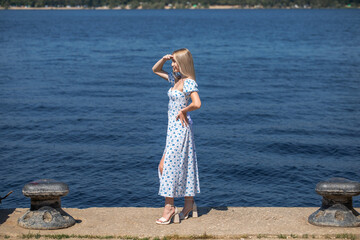 Portrait of a young beautiful blonde woman in a white summer dress