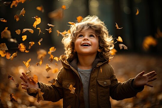 Little boy having fun during stroll in the forest at sunny autumn day. Child playing maple leaves. Baby tossing the leaves up. Active family time on nature. Hiking with little kids. Dry leaves rustle.