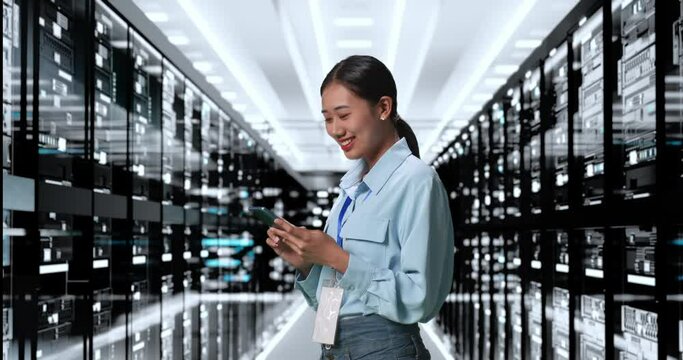 Side View Of Asian Woman Working In Server Room Database. Smiling And Shaking Head While Using Smartphone Managing Supercomputer Network
