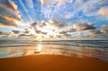 Colorful ocean beach sunrise with deep blue sky and sun rays.