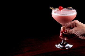 mixology female hand showing red fruit cocktail with highlighted cherry