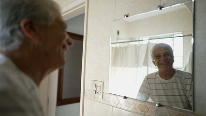 Happy senior man staring at his own bathroom reflection smiling, older person starting the day with...