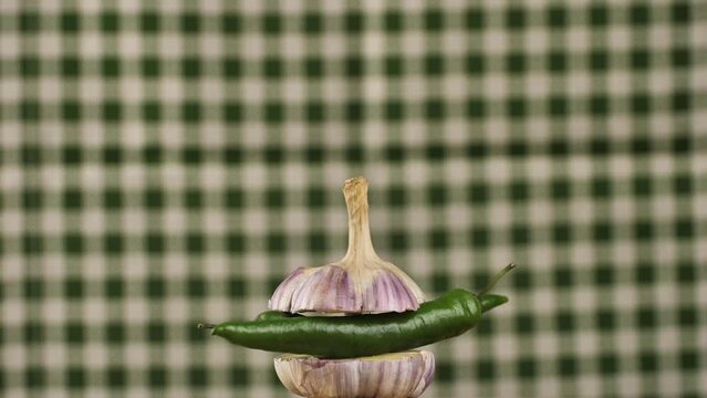 rotating young garlic with hot pepper inside on a checkered background.Young garlic and peppers are hot and tender.