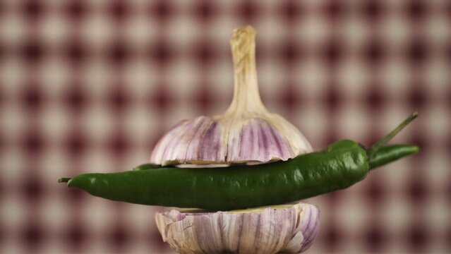 rotating young garlic with hot pepper inside on a checkered background.Young garlic and peppers are hot and tender.