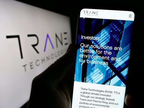 Stuttgart, Germany - 08-11-2023: Person holding mobile phone with website of Irish company Trane Technologies plc on screen in front of logo. Focus on center of phone display.