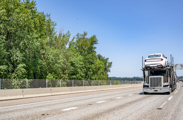 Classic big rig car hauler semi truck transporting cars on the hydraulic two level semi trailer...