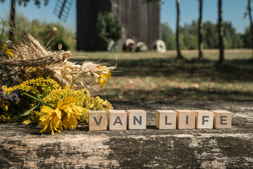bukiet z kwiatów łąkowych na ławce przy drewnianych kostkach z napisem VAN LIFE