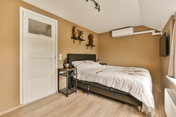 a bedroom with an air condition system on the wall, and a bed in the room has wood flooring