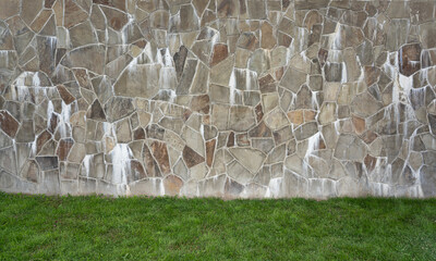 Retaining wall with natural stone mosaic structure, freshly mowed lawn