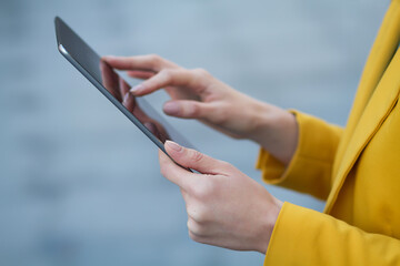 Business woman in a yellow jacket with a tablet