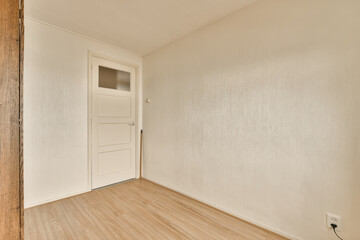 an empty room with wood flooring and white wallpaper on the walls there is a door in the corner