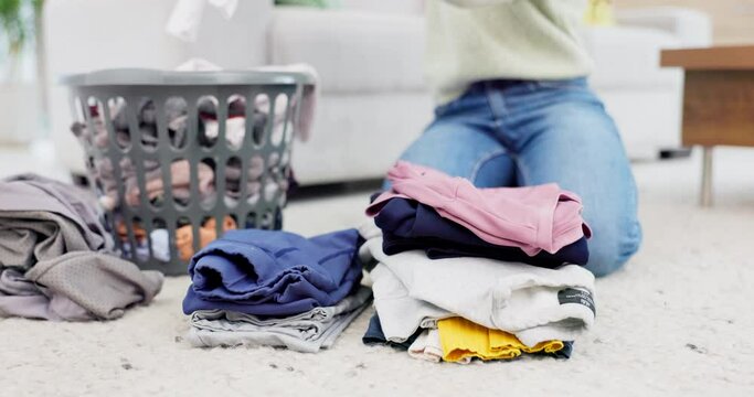 Hands, fold laundry and person with pile of clean clothes in house on living room floor or housekeeper in spring cleaning. Washing, basket and order clothing by color or woman work in home service