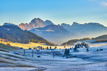 Beautiful view of traditional wooden mountain chalets on scenic Alpe di Siusi with famous Langkofel...