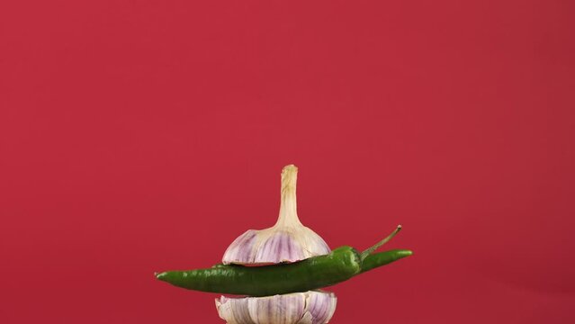 rotating young garlic with hot pepper inside on a checkered background.Young garlic and peppers are hot and tender.