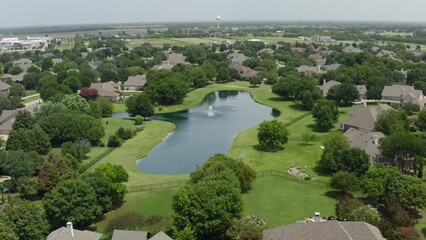 Wraparound aerial view of large water feature pond in affluent neighborhood