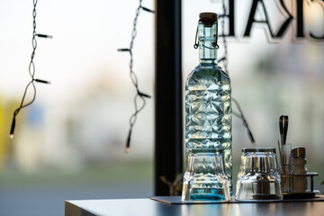 Cold fresh water in old-fashioned bottle with glasses on a cafe table