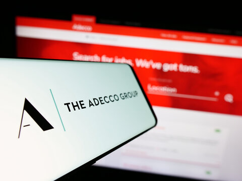 Stuttgart, Germany - 08-13-2023: Mobile phone with logo of human resources company The Adecco Group AG on screen in front of website. Focus on center-left of phone display.