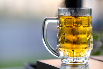Glass of light beer on a wooden table in a restaurant