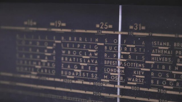 Sliding motion shot of an old radio frequency grid with the European cities. Close up shot of 1950s radio while selecting the frequency of the station