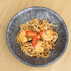 Udon noodles with shrimp and fried vegetables in a bowl top view