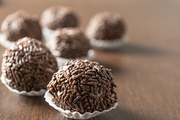 brazilian brigadeiro (brigadier) with chocolate sprinkles over wooden table. traditional brazilian candy for party dessert