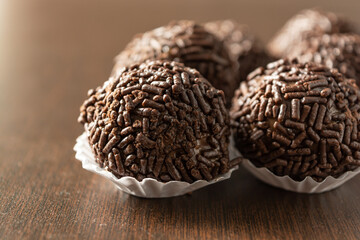 brazilian brigadeiro (brigadier) with chocolate sprinkles over wooden table. traditional brazilian candy for party dessert