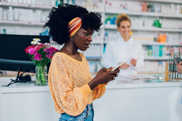 African american woman using a smartphone while shopping in a pharmacy