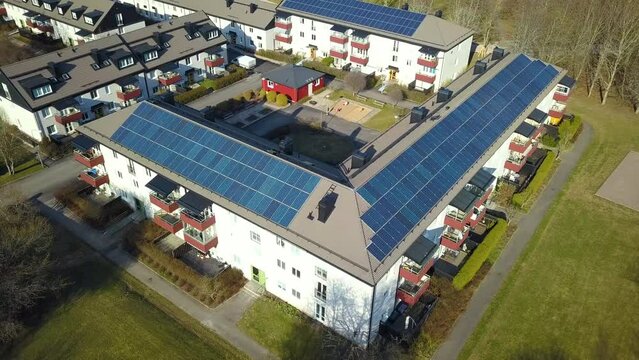 Aerial view of swedish apartment building covered with solar photovoltaic panels in Linkoping residential area. Renewable electricity development
