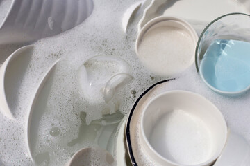 Dishes and bowls in water and bubbles of dishwashing liquid. Kitchen work