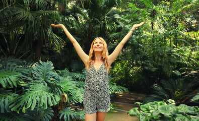 Happy smiling young woman enjoying nature in forest on tropical tree background