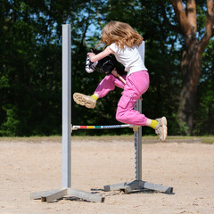 Girl jumping on hobby horse. Champion. Horse sport. Summer light. Green outdoor trees background....