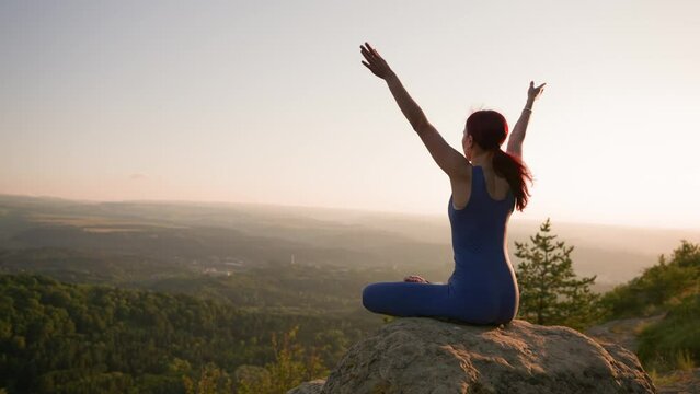 Athletic Woman Doing Yoga Poses on Top of a Mountain During Sunset. Sports Girl Trains and Does Stretching Exercises in the Mountains. Healthy Lifestyle, Zenism, Workout Concept. Slow Motion.