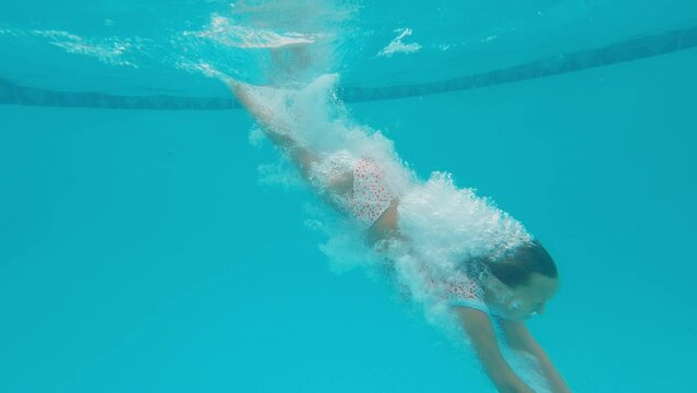 10 year old girl dives into pool, touches the bottom, resurfaces in slow motion