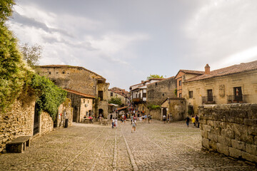 Obraz premium Old Town Street with Cobbled Floor and People Walking in the Background. Rural Tourism Concept