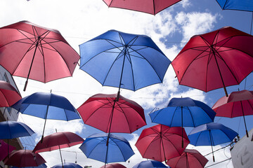 several blue and red parasols hanging on a sunny day