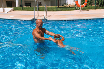 Naklejka premium dad swims with his son in the pool playing