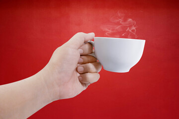 hand holding white coffee cup with red background