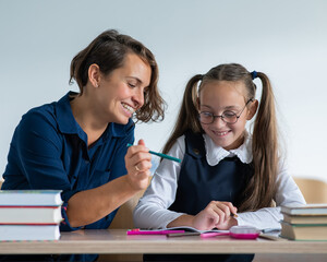 The teacher explains the task to the schoolgirl in the classroom.