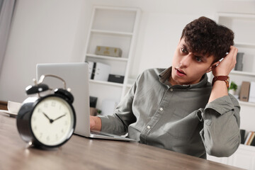 Obraz premium Emotional young man working at table in office. Deadline concept