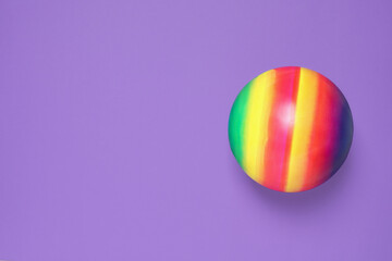 New bright kids' ball on purple background, top view. Space for text