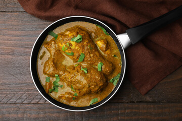 Delicious chicken with curry sauce on wooden table, top view