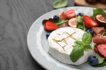 Delicious salad with brie cheese, blueberries, figs and strawberries on grey wooden table, closeup