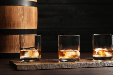 Glasses of tasty whiskey on table against dark background